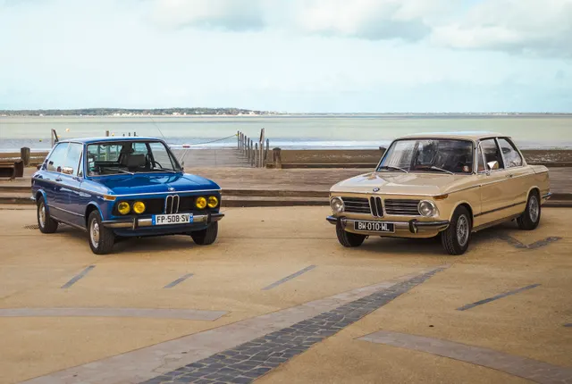 BMW et berline ancienne exposées en bord de mer